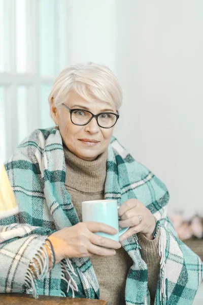 Ältere Frau mit kariertem Karo trinkt zu Hause Tee — Stockfoto