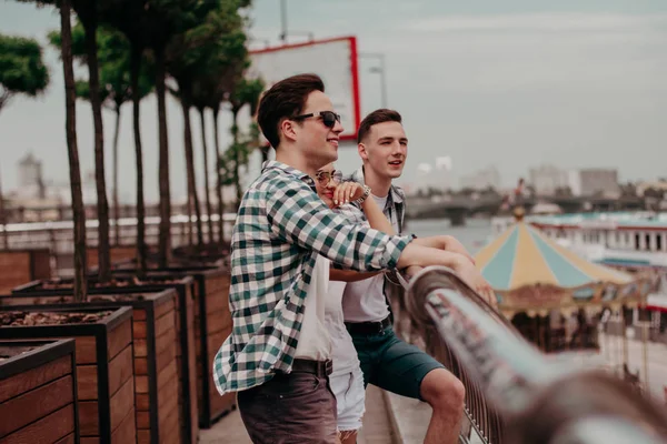 Drei junge Freunde auf Brücke und Blick auf die Stadt. — Stockfoto