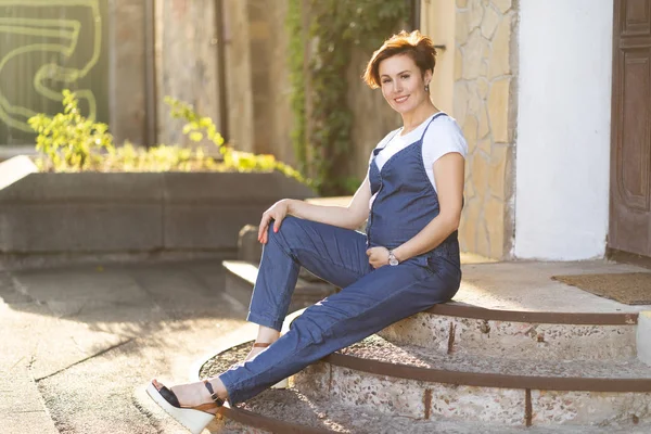 Mujer Embarazada En Mono Azul Sentada En Pasos Al Aire Libre — Foto de Stock