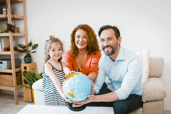 Glimlachende ouders en dochter houden wereldbol, plannen vakantie. — Stockfoto
