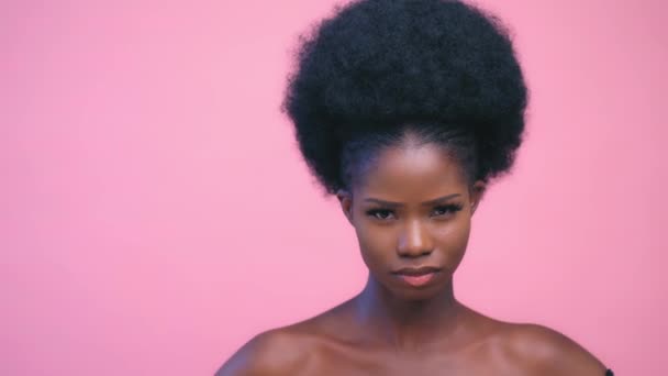 Seksi Afro-Amerikan modeli gülümsüyor ve pembe arka plan pozu veriyor. — Stok video