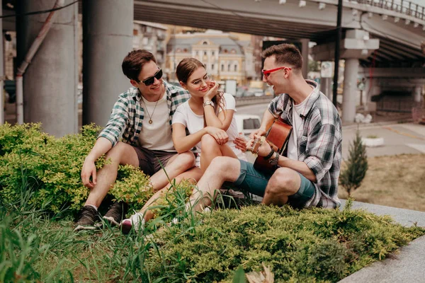 ギターを持つ若者は草の上に座って楽しむ — ストック写真