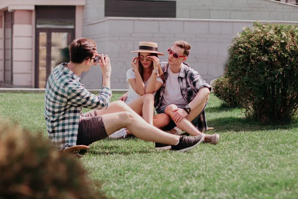 Młodzieżowa firma robi zdjęcia siedząc na słonecznym trawniku — Zdjęcie stockowe