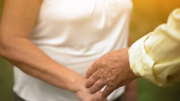 Un hombre y una mujer tocan las manos en el jardín —  Fotos de Stock