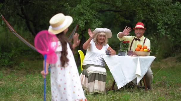 Jeune dame mignonne avec un filet papillon rose et ses grands-parents — Video