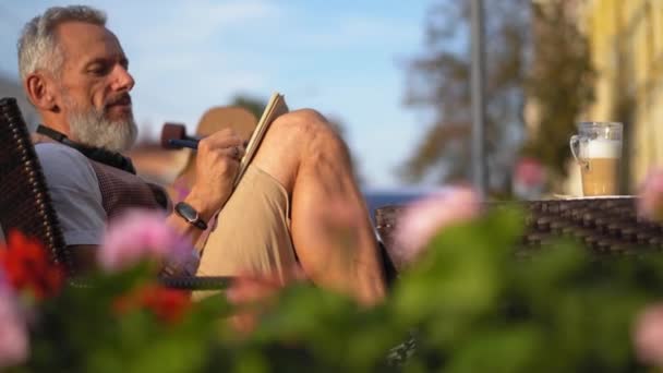 Успішний письменник із запалом бере примітки розслабляючись у сонячний ранок на відкритому повітрі — стокове відео