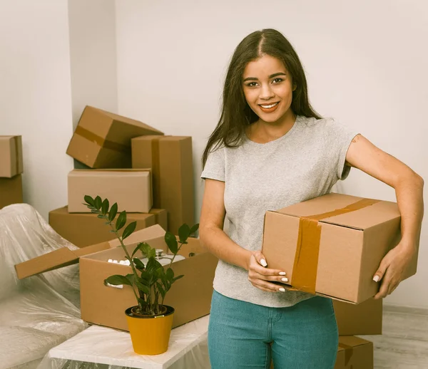Beautiful hispanic female standing with box in new home — 스톡 사진