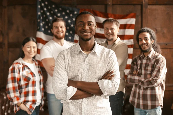 Diverso equipo patriótico americano de pie sobre la bandera de los estadounidenses espalda — Foto de Stock
