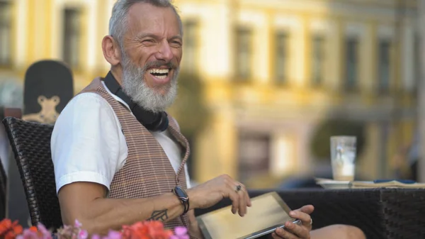 A middle-aged European man works privately with a tablet in a street cafe — стокове фото