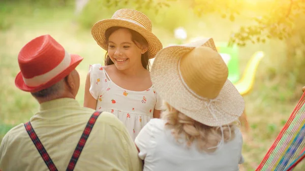 La vieja pareja está sentada en la hamaca en el jardín — Foto de Stock