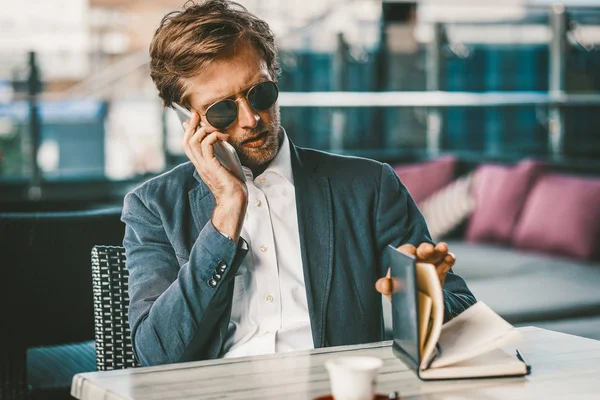 Young businessman doing schedule entrees while talking on a phone — 스톡 사진