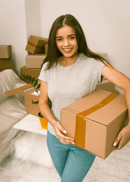 Young woman relocating, holding box ready to unpack things in newly rented apartment.