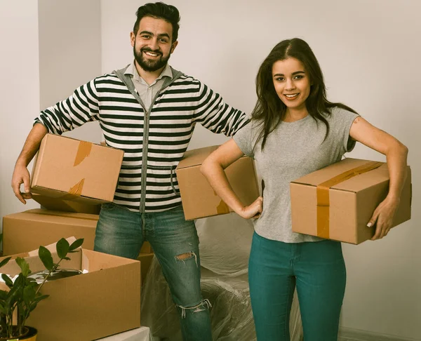 Happy husband and wife carrying boxes in their new house. — Stock Photo, Image