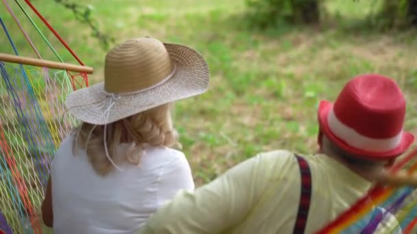 The Old Couple Is Sitting In The Hammock In The Garden — Stockvideo