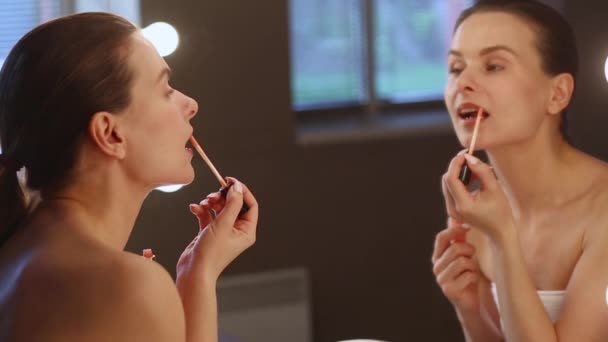 Mladá bruneta Apllying rtěnka při pohledu na zrcadlo — Stock video