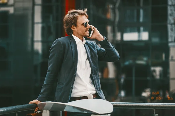 Joven exitoso feliz sonriendo mientras tiene conversación telefónica — Foto de Stock