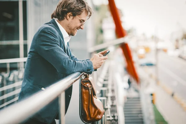 Hezký podnikatel pracující na chytrém telefonu mimo obchodní centrum — Stock fotografie