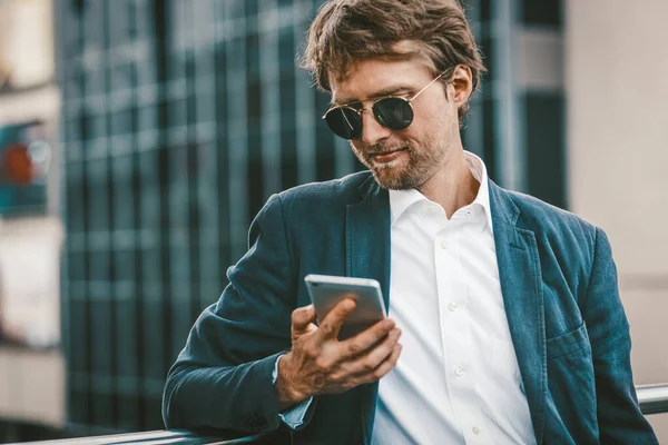 Mladý obchodník venku. Muž pracující online stojící na ulici. — Stock fotografie