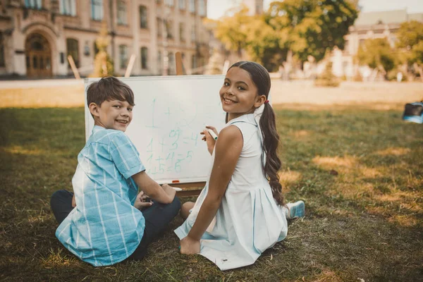 Fröhliche Kinder schreiben in der Natur Zahlen auf Whiteboard — Stockfoto