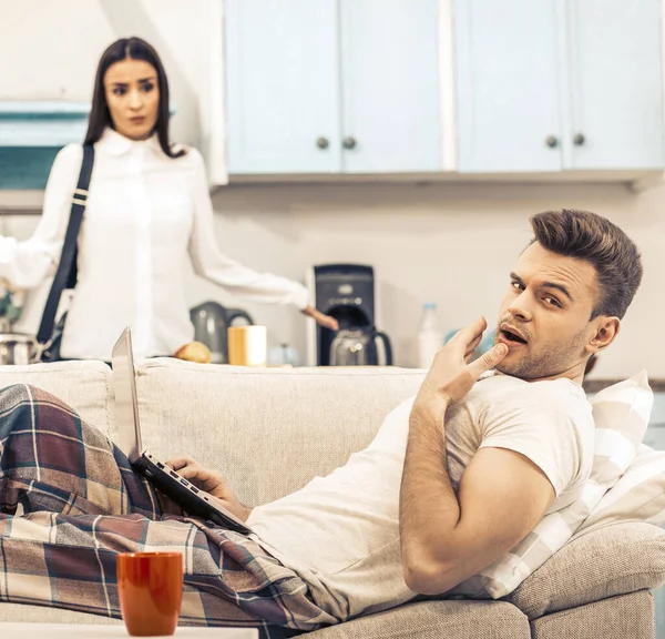 Man in pyjama geeuwt terwijl liggend op de bank — Stockfoto