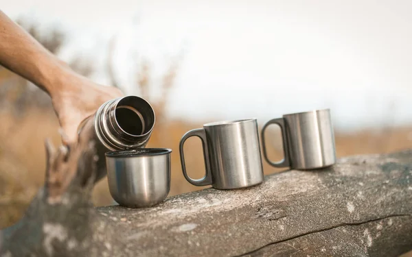 Männliche Hände gießen Heißgetränk aus Thermoskannen in Becher — Stockfoto