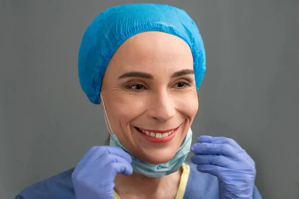 Femeia medic zâmbește îndepărtând masca chirurgicală — Fotografie, imagine de stoc