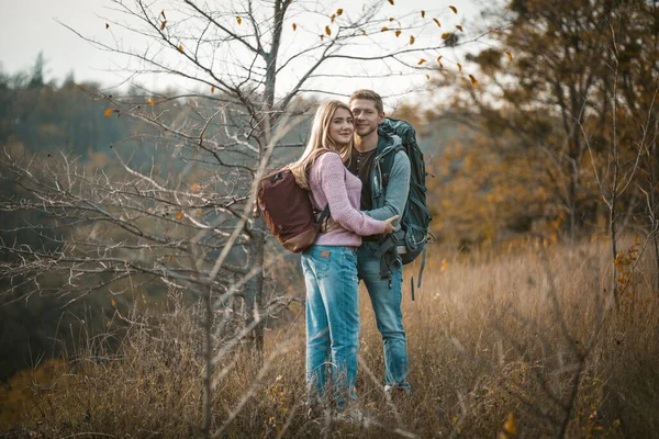 Pareja sonriente con mochilas de pie abrazada — Foto de Stock