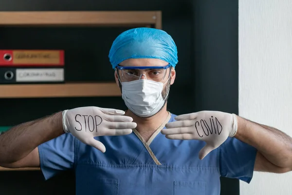 Un bărbat în uniformă medicală albastră arată sloganul pentru a opri Covid — Fotografie, imagine de stoc