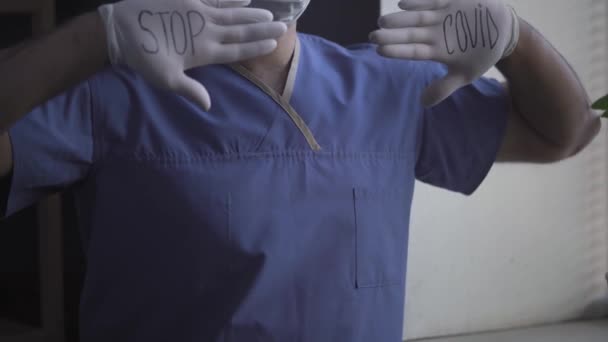 Docteur disant ARRÊT COVID écrit sur ses gants . — Video