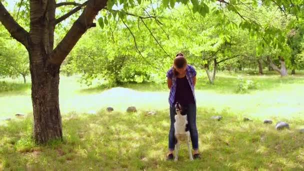 Dívka trénuje svého psa venku stojící vedle něj. — Stock video