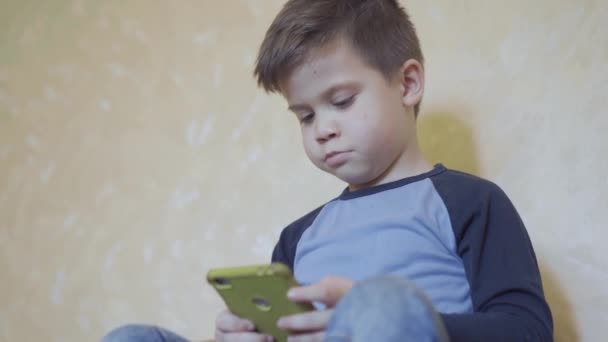 Garçon tenant smartphone payer des jeux éducatifs . — Video