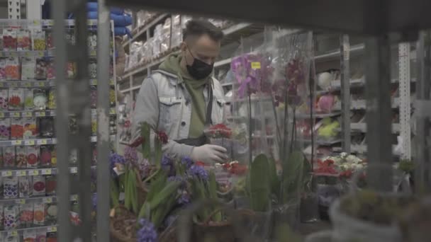 Mann mit Schutzmaske sammelt Topfblumen für Ehefrau ein. — Stockvideo