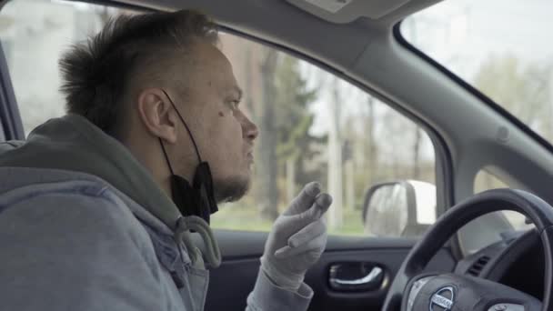 Fahrer berührt sein Gesicht mit dispositiven Handschuhen im Stehen auf Licht. — Stockvideo