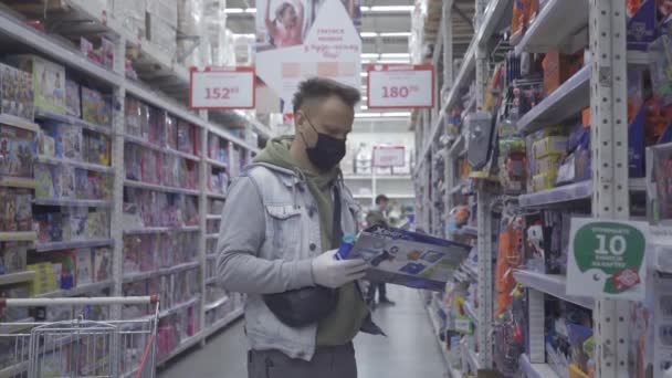 Человек носит маску многоразового использования на лице, делая продуктовый магазин для семьи . — стоковое видео