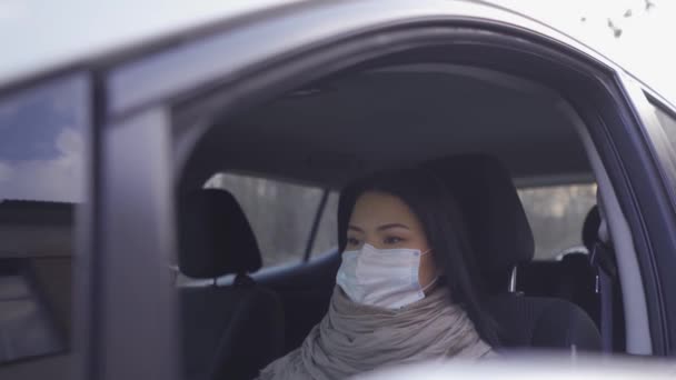 Asiatin in Maske sitzt im Auto. — Stockvideo