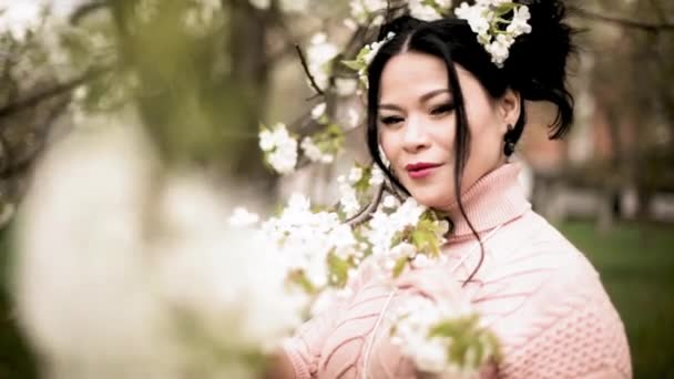 Gyönyörű középkorú női modell a nyári virágos parkban. — Stock videók
