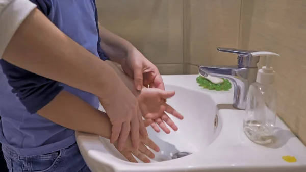 小さな手を洗うために息子を助ける母親 — ストック写真