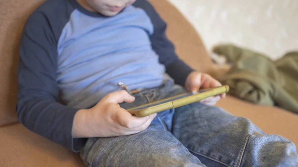 El niño usa el teléfono para jugar o aprender a quedarse en casa — Foto de Stock