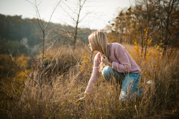 Mooie vrouw hurken op klif rand bij gras — Stockfoto