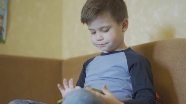 Мальчик исправляет волосы, играя в игры на смартфоне . — стоковое видео