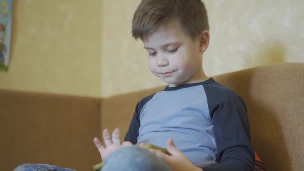 Menino corrige seu cabelo enquanto joga jogos no smartphone . — Vídeo de Stock