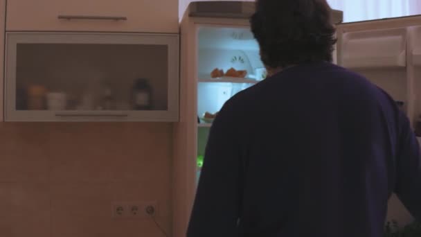 Un hombre parado frente a un refrigerador — Vídeos de Stock