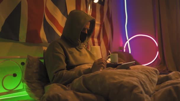 Uomo con influenza rimane a casa sdraiato a letto con tablet e social media . — Video Stock