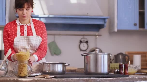 Žena vařící špagety v kuchyni v červených šatech. Vtipný kuchař otevře konvici s vařící vodou a dá do ní špagety. Prores 422 — Stock video