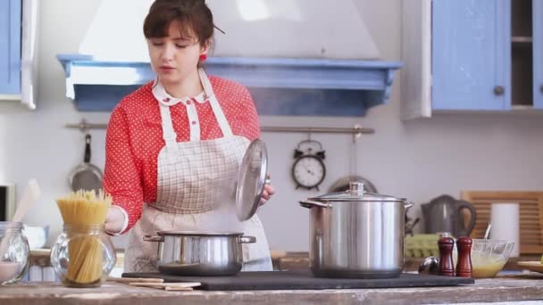 아름다운 여성 이 낡은 주방에서 빨간 드레스를 입은 스파게티를 만들고 있습니다. 건강 한 가정의 어머니는 코로나 바이러스가 유행하는 동안 사랑하는 가족을 위해 음식을 만들었습니다. 프로방스 422 — 비디오