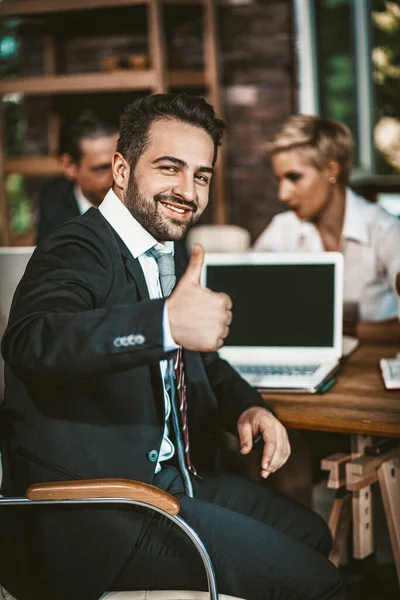 Leende affärsman visar tummen upp gest sitter på möte — Stockfoto