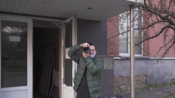 Fotograf robiący zdjęcia na zewnątrz, trzymający cyfrową kamerę w tle przemysłowym. Technika fotografii biznesowej. Prores 422 — Wideo stockowe
