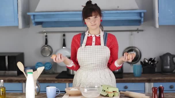 Eine Köchin mit Eiern in der Hand in einer Schraubküche kann sich nicht entscheiden, wie viele Zutaten sie zum Kochen braucht. Ein junges Mädchen kocht zum ersten Mal in einer großen Küche. Prores 422 — Stockvideo