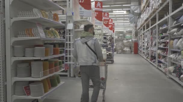 Ein Mann in einem leeren Geschäft, Einkaufszentrum macht einen Einkauf für die Familie auf der Suche nach dem richtigen Produkt. Männliche Käufer während der Coronavirus-Pandemie. Prores 422. Auchan, Kiew, Ukraine. April 2020 — Stockvideo