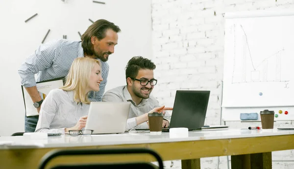 Teamwork of colleagues reading news together on a computer in light office — Stock Photo, Image